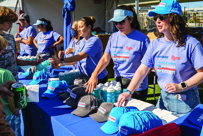 Event volunteers hand out giveaways at the Mid-Coast Trolley Grand Opening Celebration