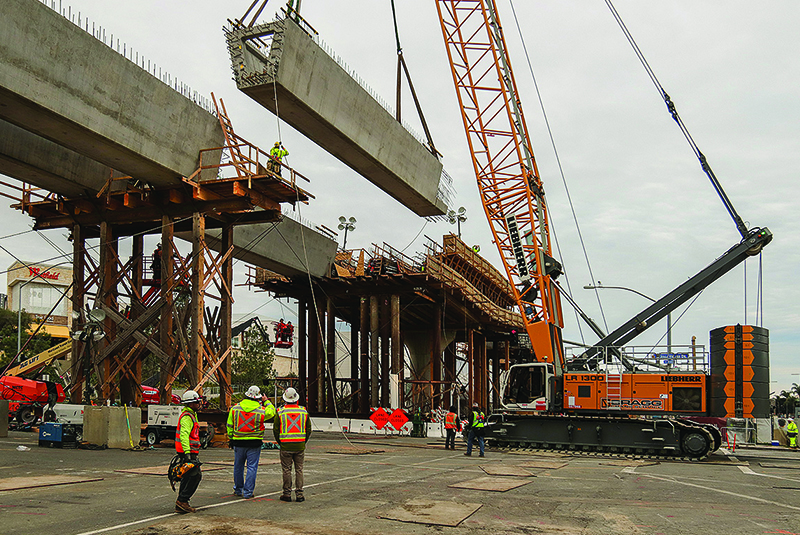 Crews hoist concrete girders into place along Genesee Avenue, to form the Trolley bridge. (February 2019)