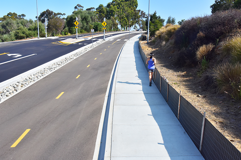 A woman in purple runs on the new pedestrian path along Pershing Drive. 