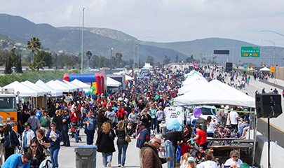 Photo of the SR 52 highway grand opening event showing a large gathering of people celebrating on the closed off highway.